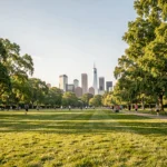 Vue panoramique de Corona Park à Queens, New York, par une journée ensoleillée avec des familles se promenant sur les pelouses verdoyantes devant le skyline de Manhattan