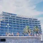 people sitting on concrete bench near white concrete building during daytime