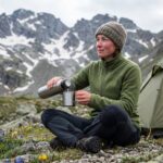 Femme en camping en montagne avec thermos et tente