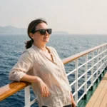 Femme en croisière sur la Méditerranée, accoudée au bastingage d'un paquebot avec vue sur la mer depuis Marseille