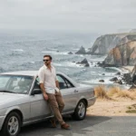 Homme appuyé contre une voiture de location sur une route panoramique de la côte californienne entre Los Angeles et San Francisco